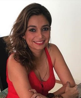 Mercedes Lucía Posada Meola sits learning forward with arms resting on a table. She wears a red tank top and looks directly at the camera. The photo background is white.